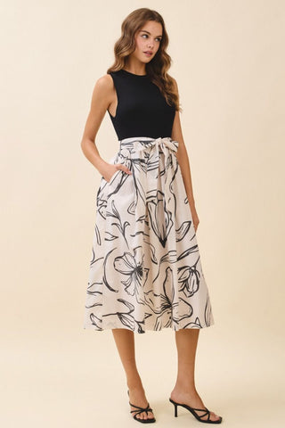 Woman wearing a black top and floral skirt on a beige background