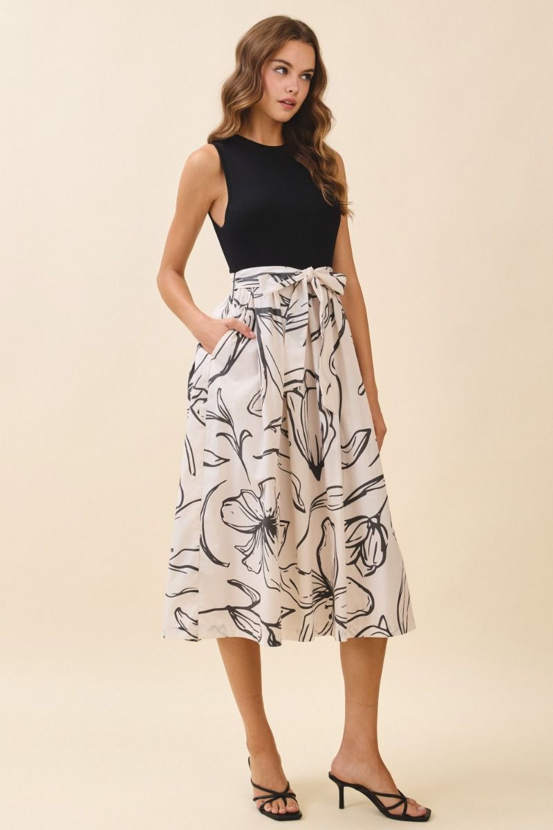 Woman wearing a black top and floral skirt on a beige background