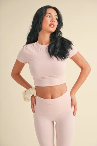 Woman wearing a light pink athletic outfit on a beige background