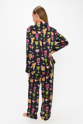 Person wearing a black pajama set with colorful cocktail print on a white background