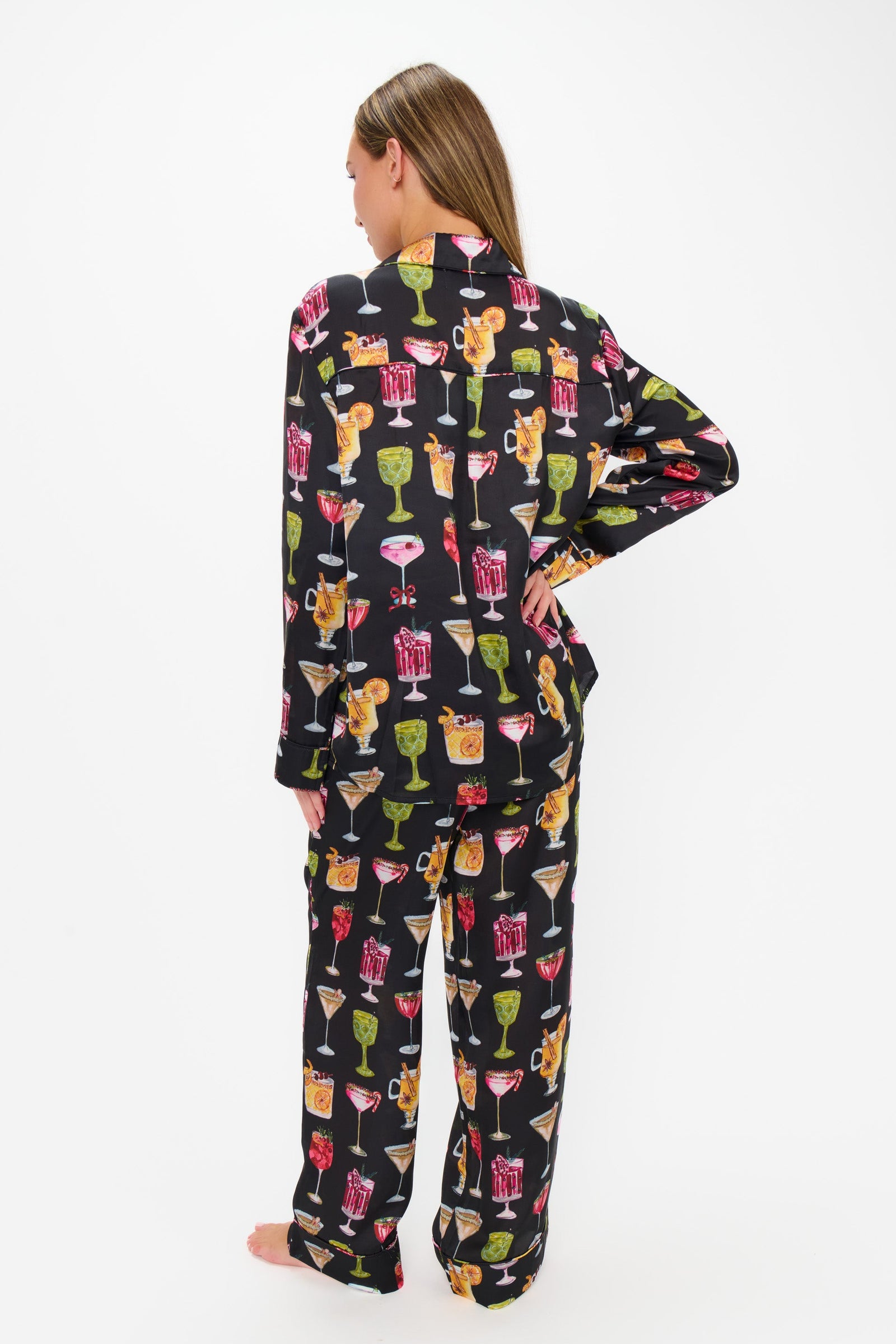 Person wearing a black pajama set with colorful cocktail print on a white background