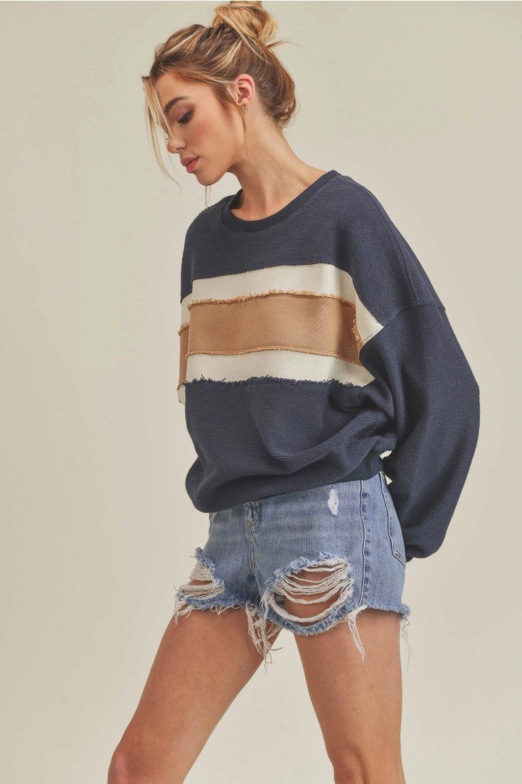 Woman wearing a striped sweater and denim shorts on a plain background