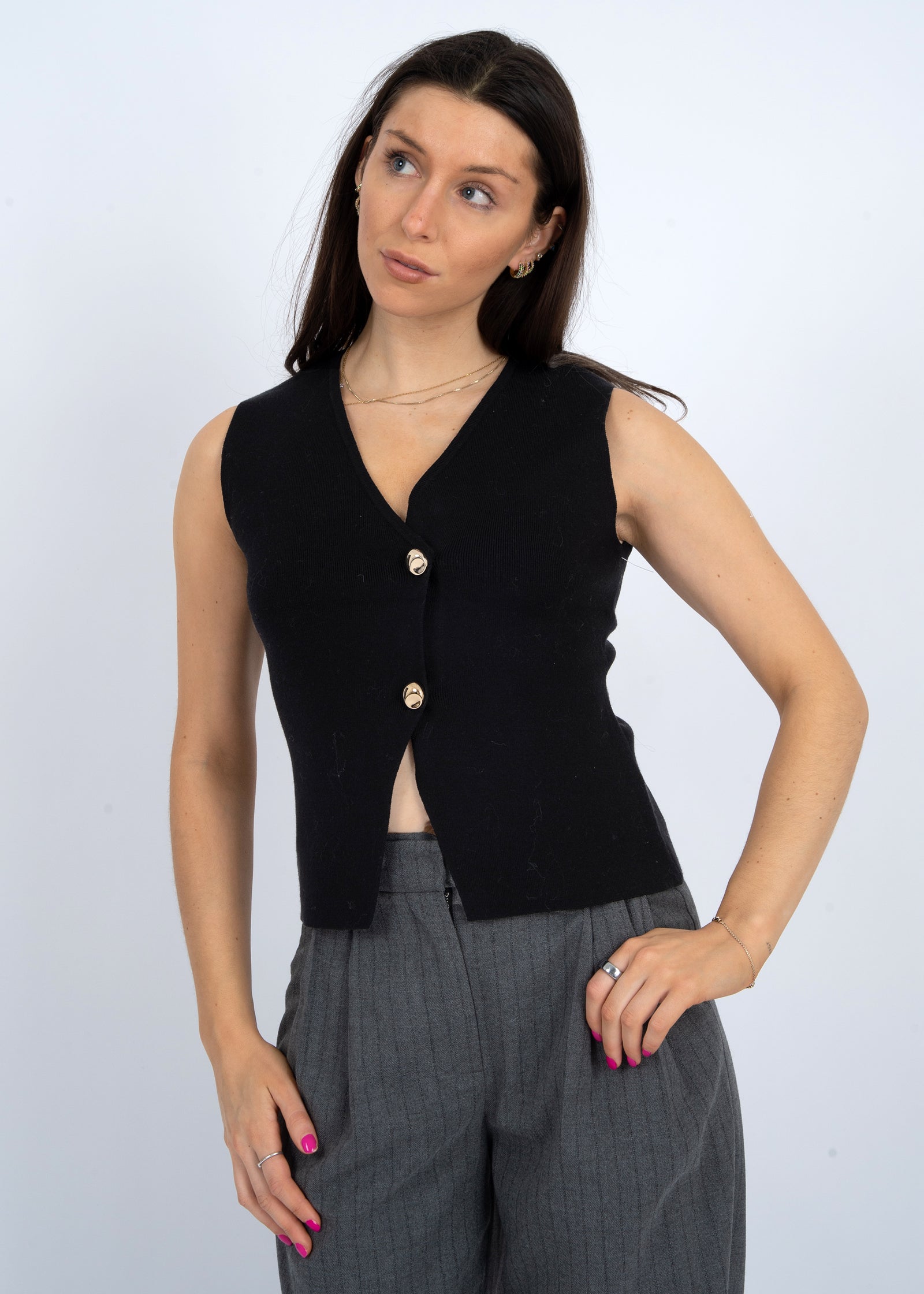 Woman wearing a black sleeveless top with buttons against a white background