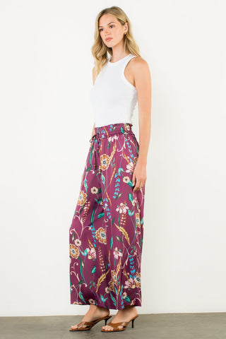 Woman wearing a white sleeveless top and purple floral skirt on a white background