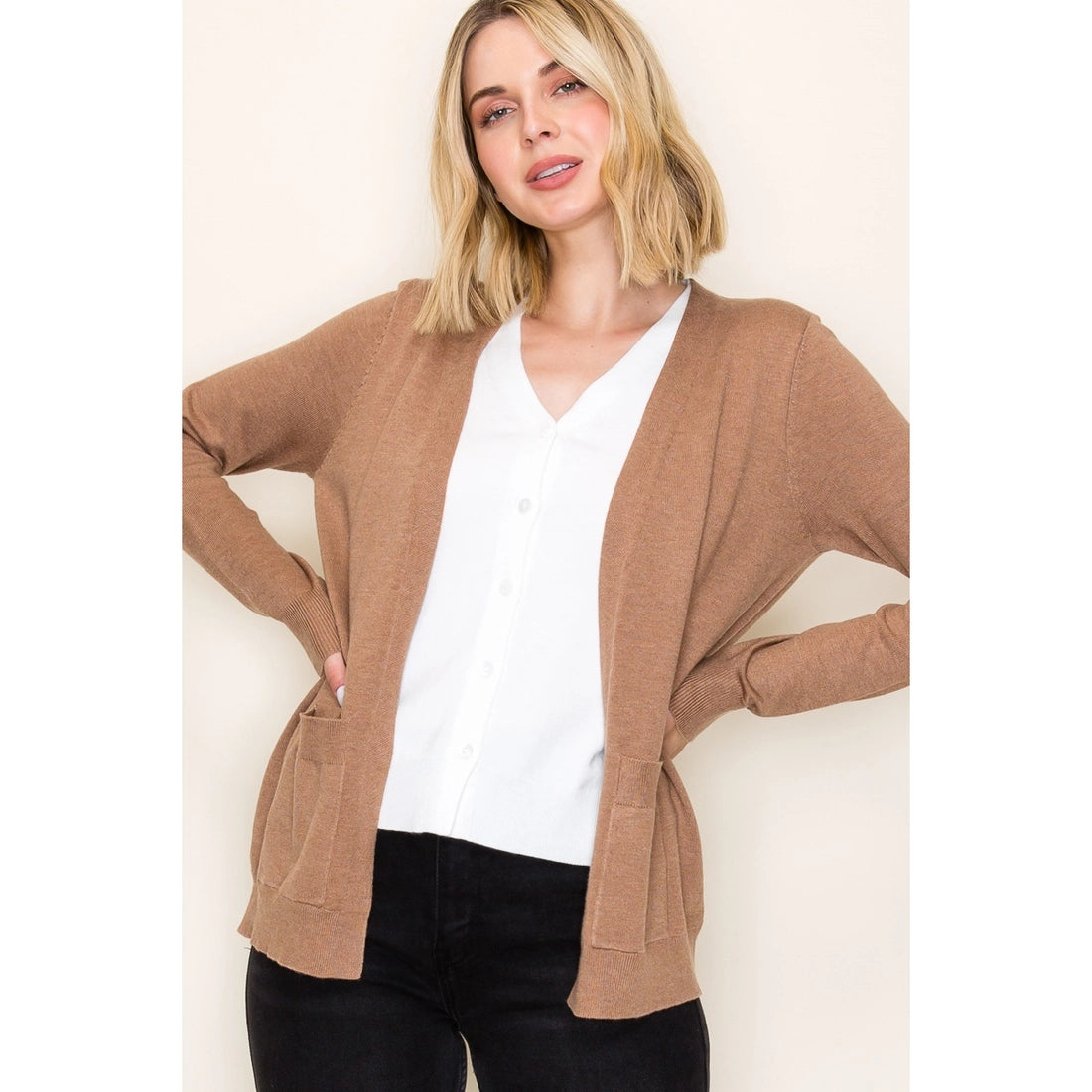 Woman wearing a brown cardigan over a white shirt on a beige background