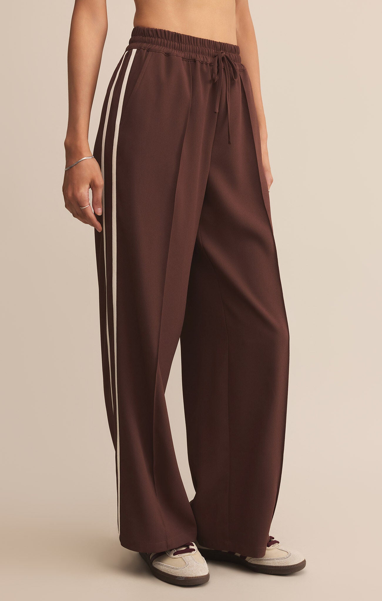 Brown wide-leg pants worn by a person on a beige background