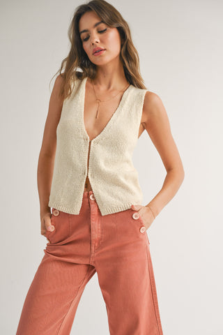 A woman wearing a beige cardigan vest  STMT BOUTIQUE 