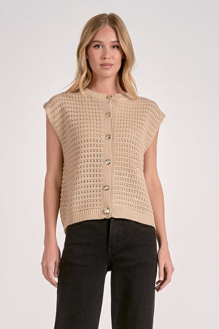 Woman wearing a beige sleeveless knitted top with buttons on a white background