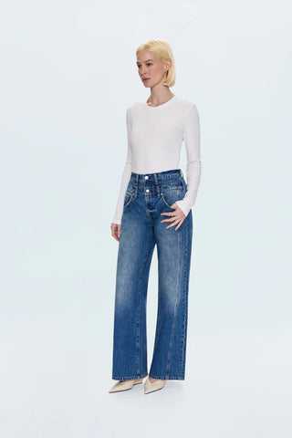 Woman wearing blue jeans and a white top on a light gray background