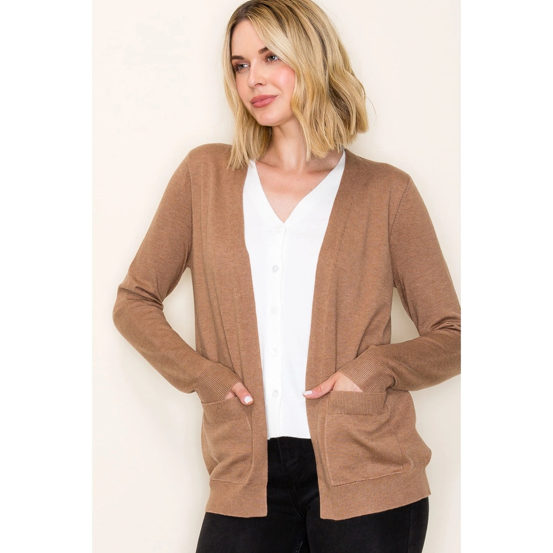 Woman wearing a brown cardigan over a white shirt with a plain background