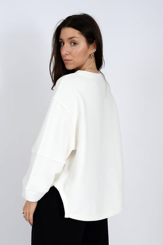 Woman wearing a white sweater against a plain background