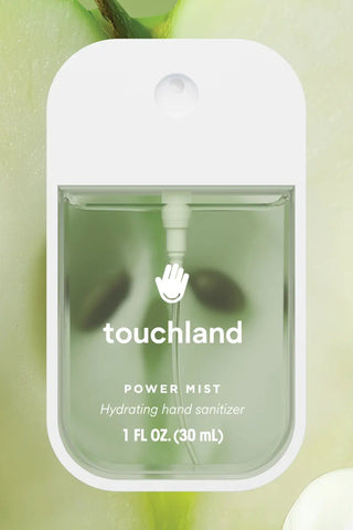 Touchland power mist hand sanitizer with green apples and white flowers in the background