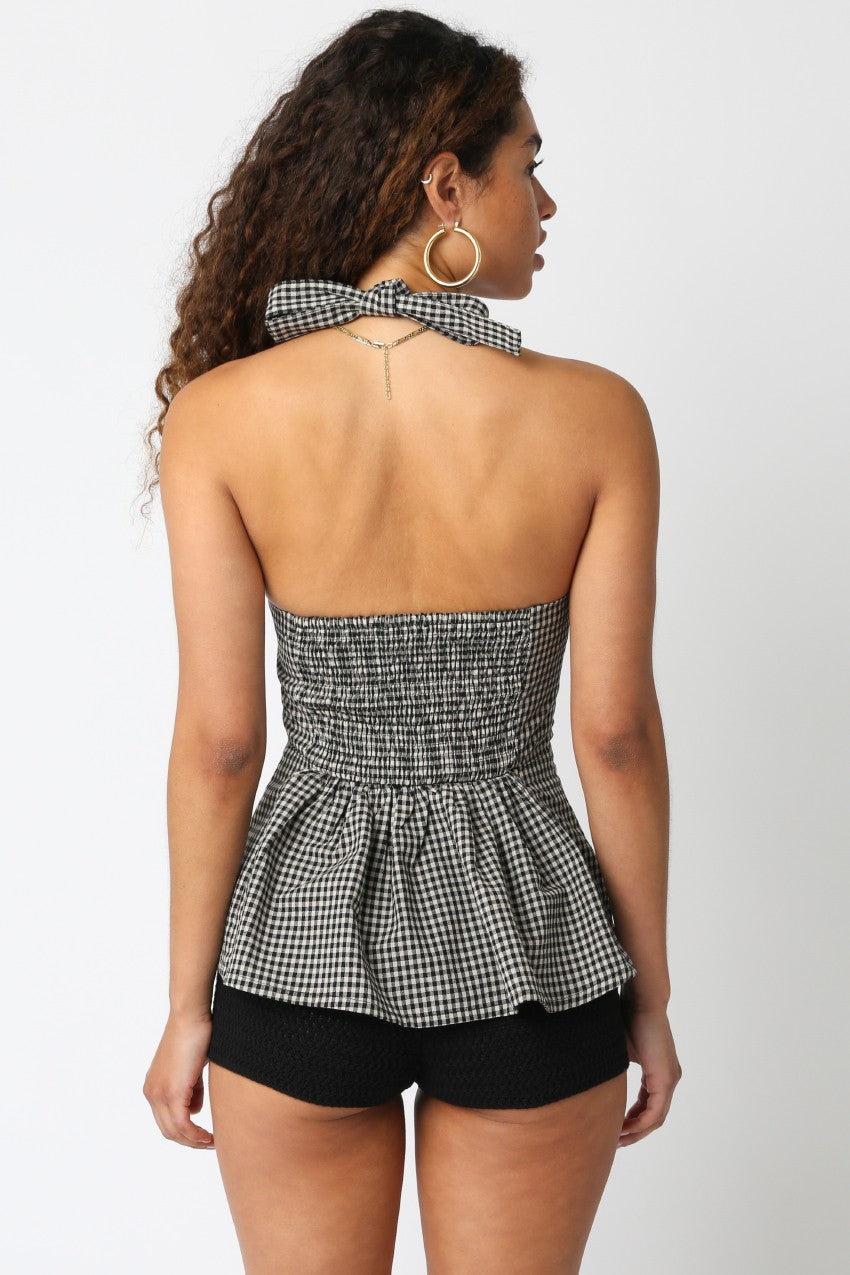 Woman wearing a black and white checkered peplum top and black shorts on a white background