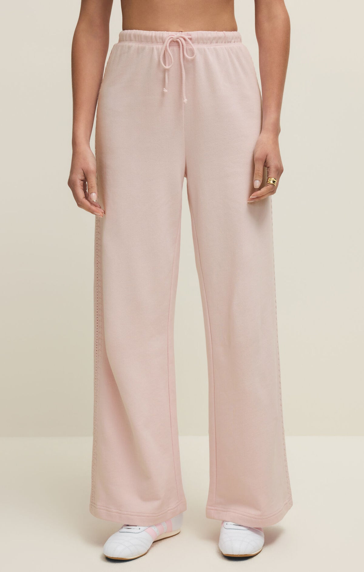 Pink wide-leg pants worn by a person on a beige background