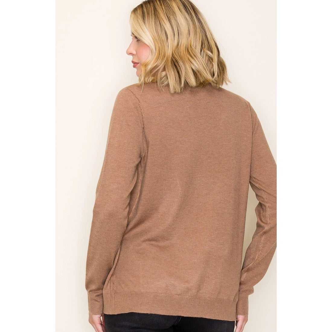 Woman wearing a brown long-sleeve top against a plain background