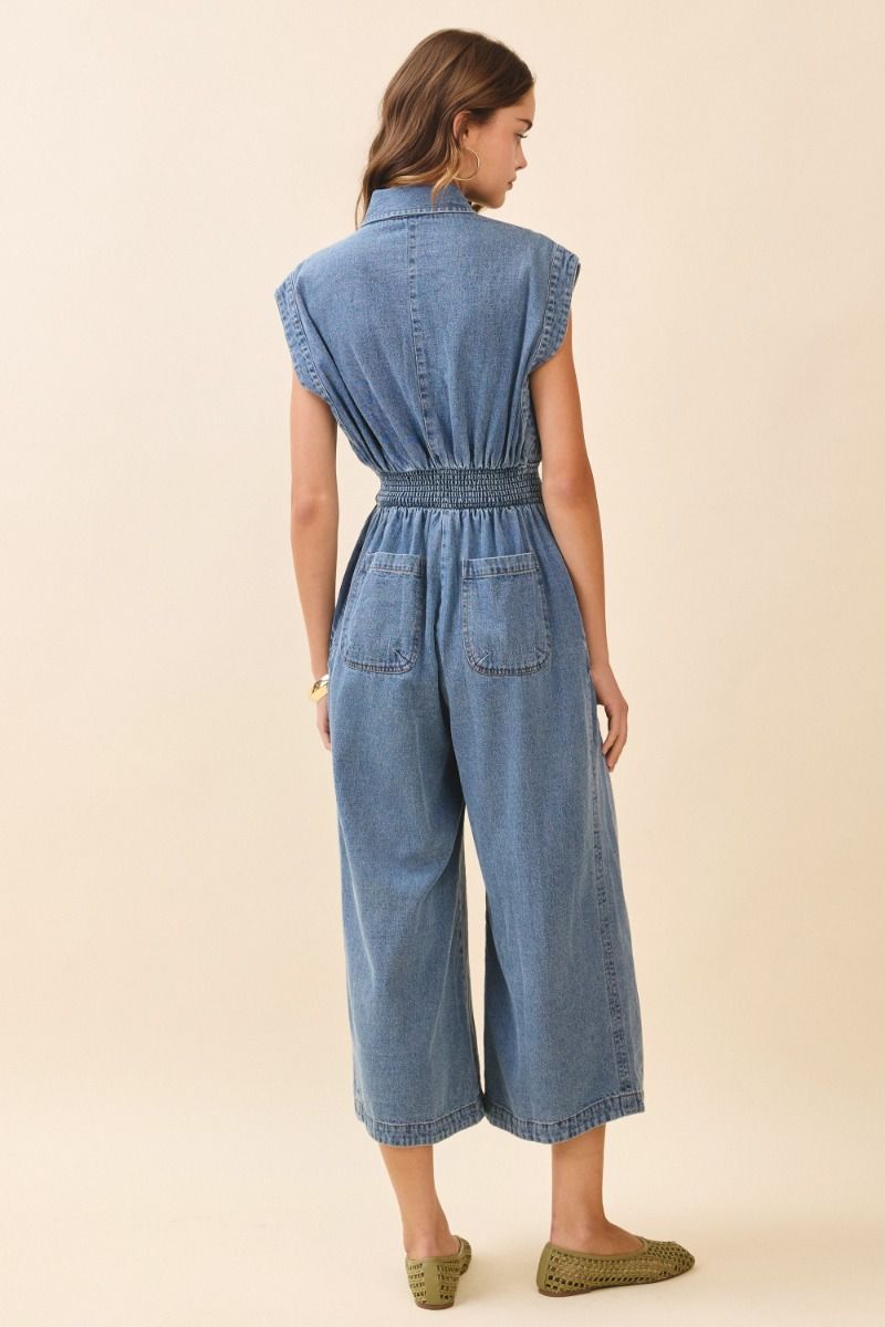 Woman wearing a denim jumpsuit on a beige background