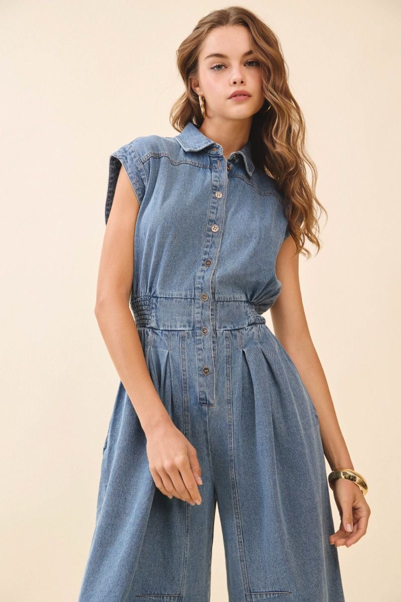 Woman wearing a denim jumpsuit against a beige background