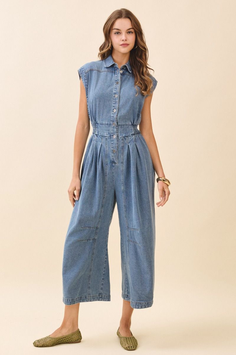 Woman wearing a denim jumpsuit on a beige background