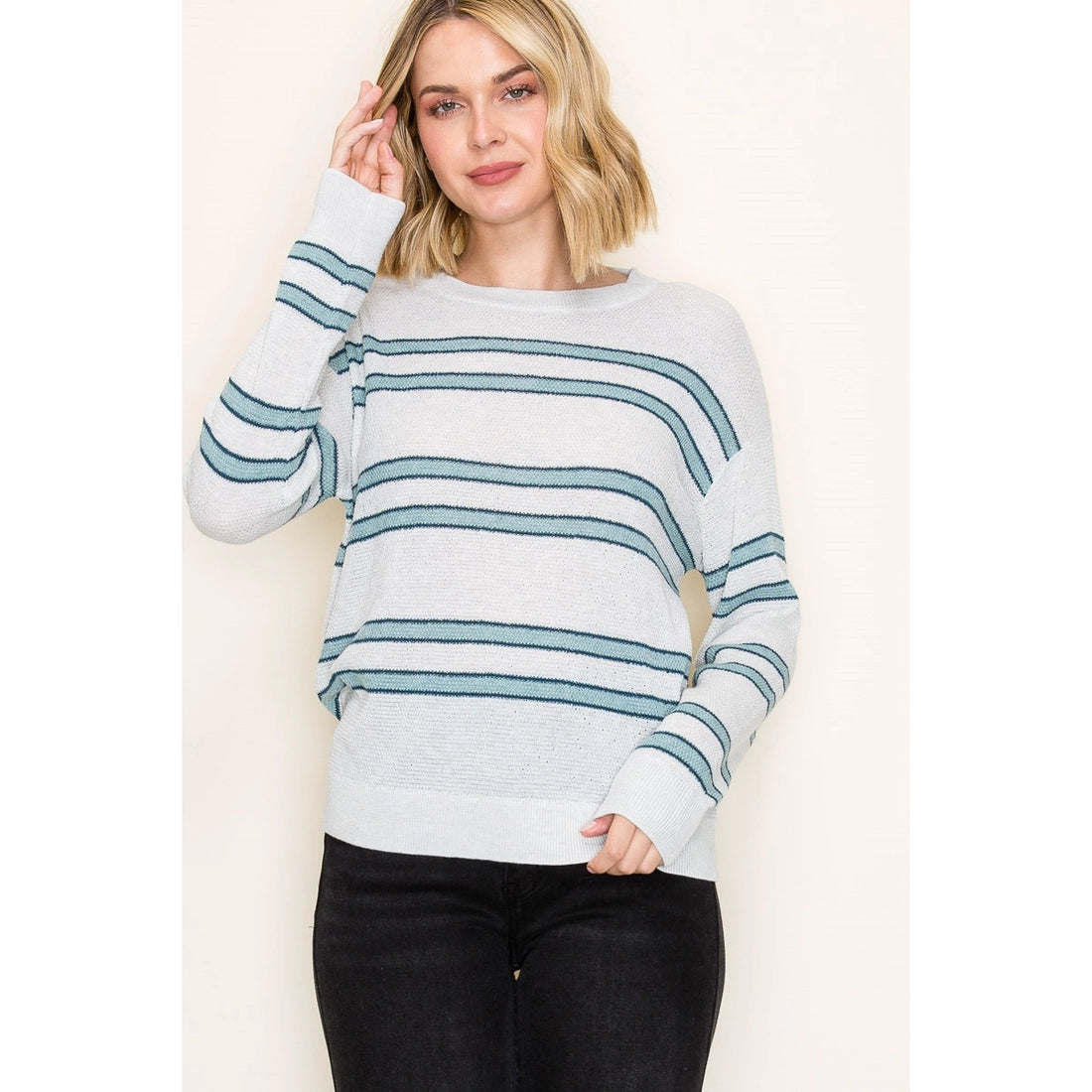 Woman wearing a light blue and white striped sweater against a plain background