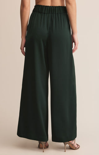 Dark green wide-leg pants worn by a person on a beige background