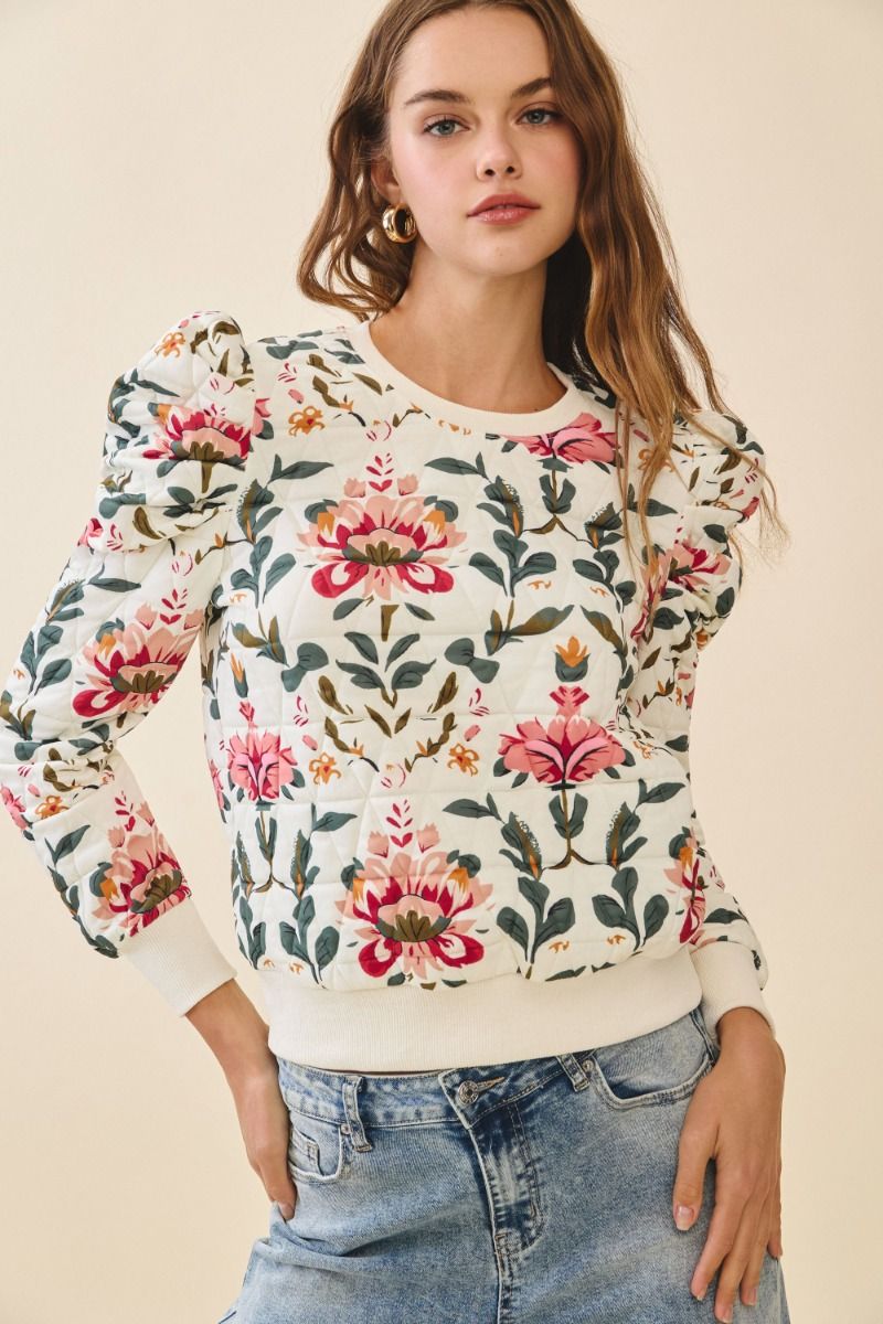 Woman wearing a floral sweater with a beige background