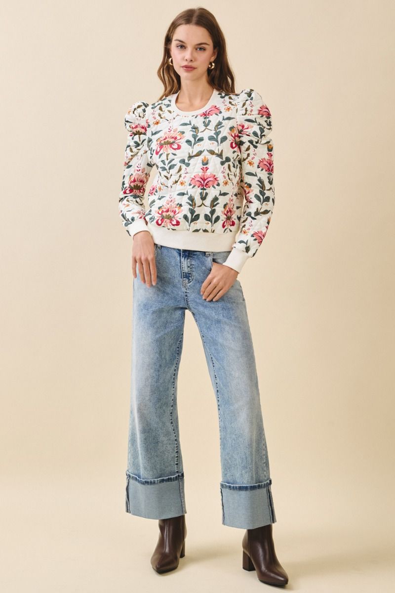 Woman wearing a floral blouse and jeans on a beige background