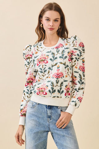 Woman wearing a floral sweatshirt and jeans on a beige background