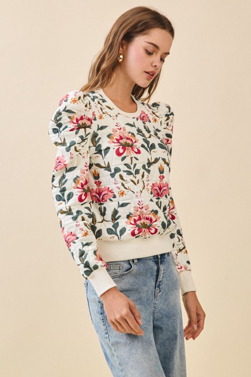 Woman wearing a floral sweater and jeans on a beige background