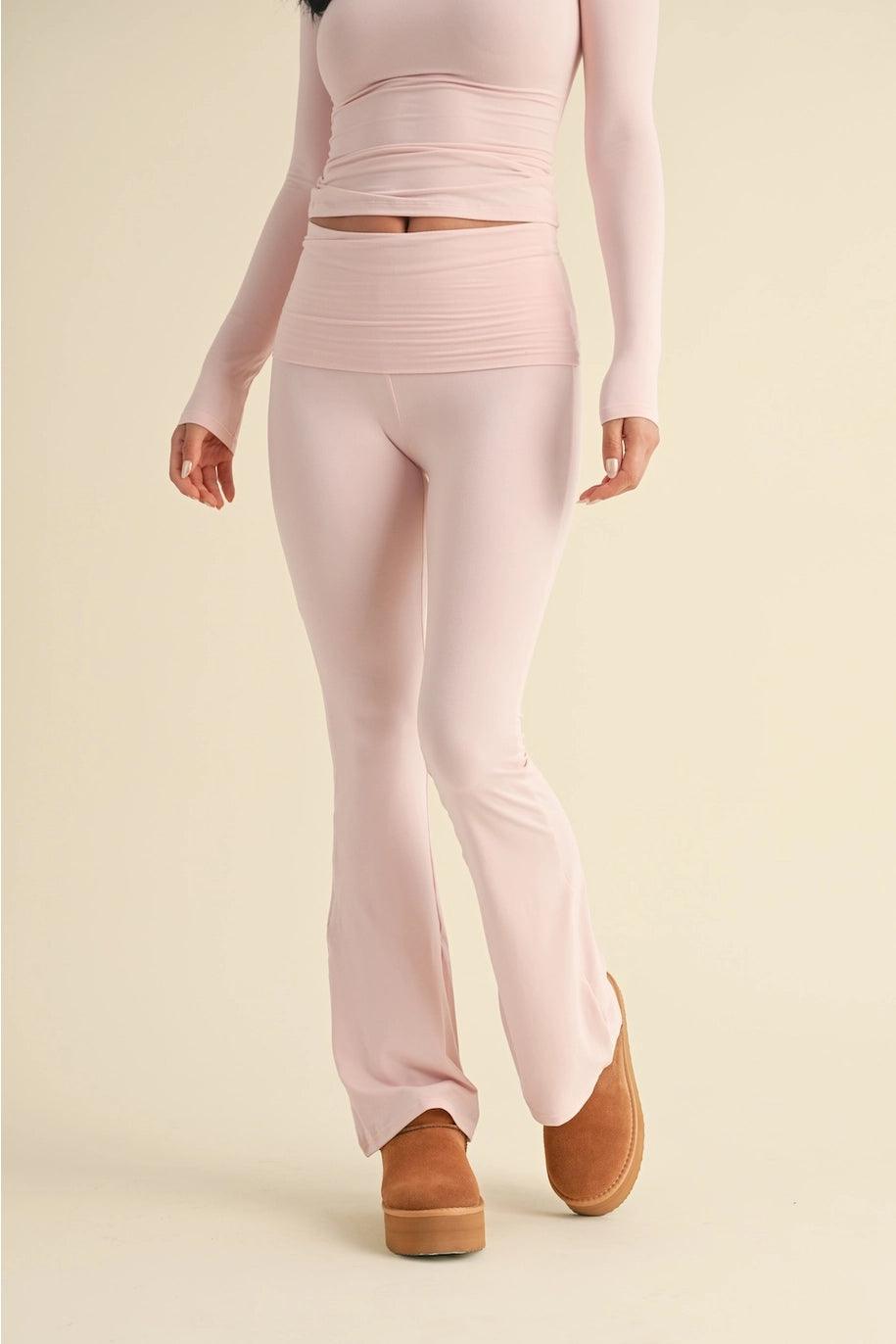 Person wearing a pink outfit with matching pants and top on a beige background