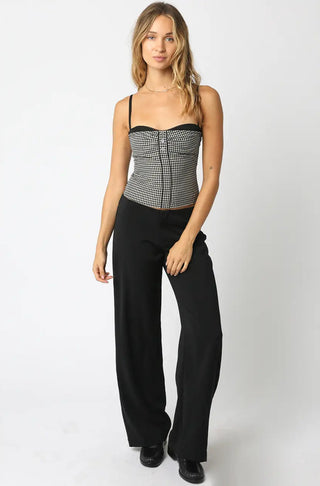 Woman wearing a black and white patterned top with high-waisted black pants on a white background