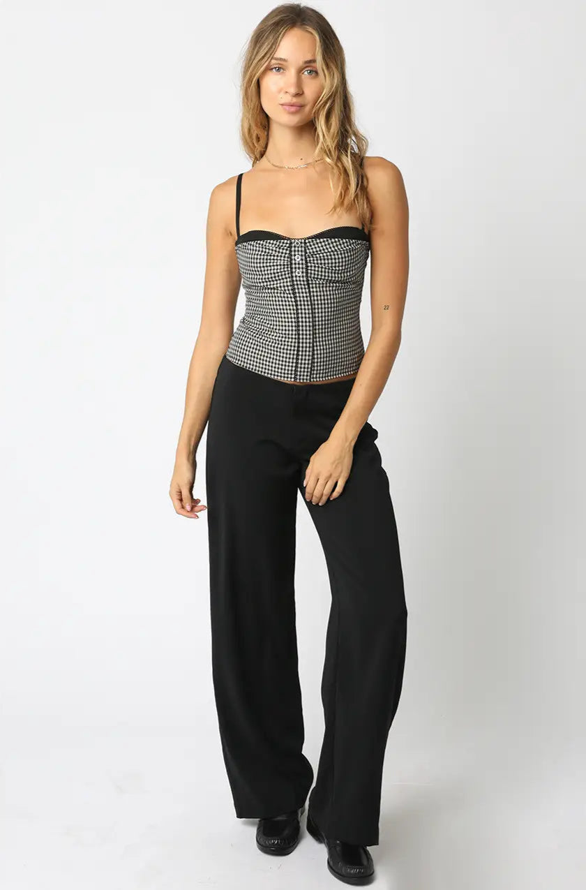 Woman wearing a black and white patterned top with high-waisted black pants on a white background