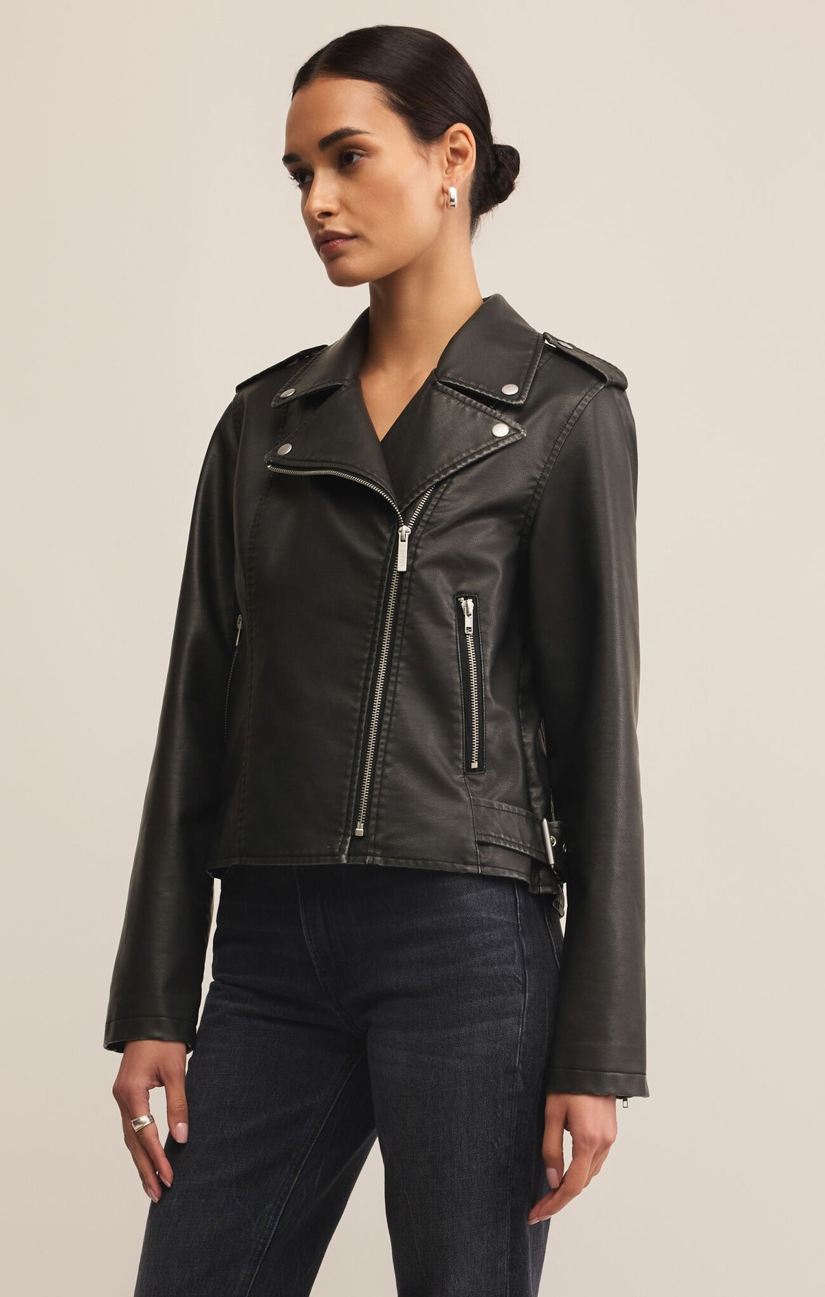 Woman wearing a black leather jacket on a beige background