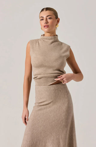 Woman wearing a beige sleeveless top and skirt set against a plain background