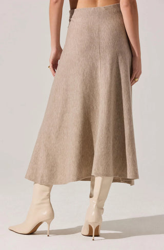 Person wearing a beige skirt and white boots on a light background