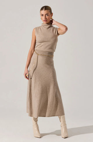 Woman wearing a beige sleeveless top and skirt with a gold belt on a white background