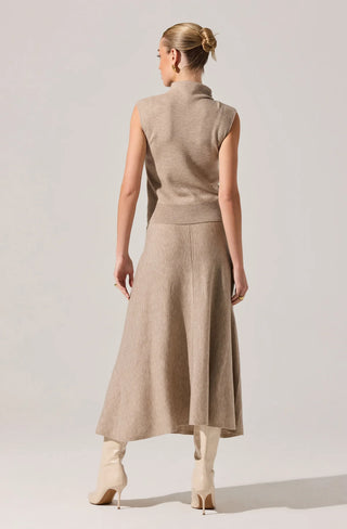 Woman wearing a beige sleeveless dress against a plain background