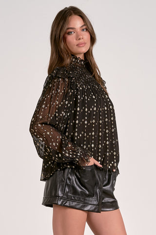 Woman wearing a black polka dot blouse and black leather shorts on a white background