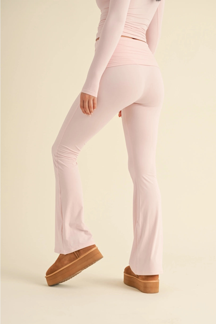 Person wearing light pink leggings and brown shoes on a beige background