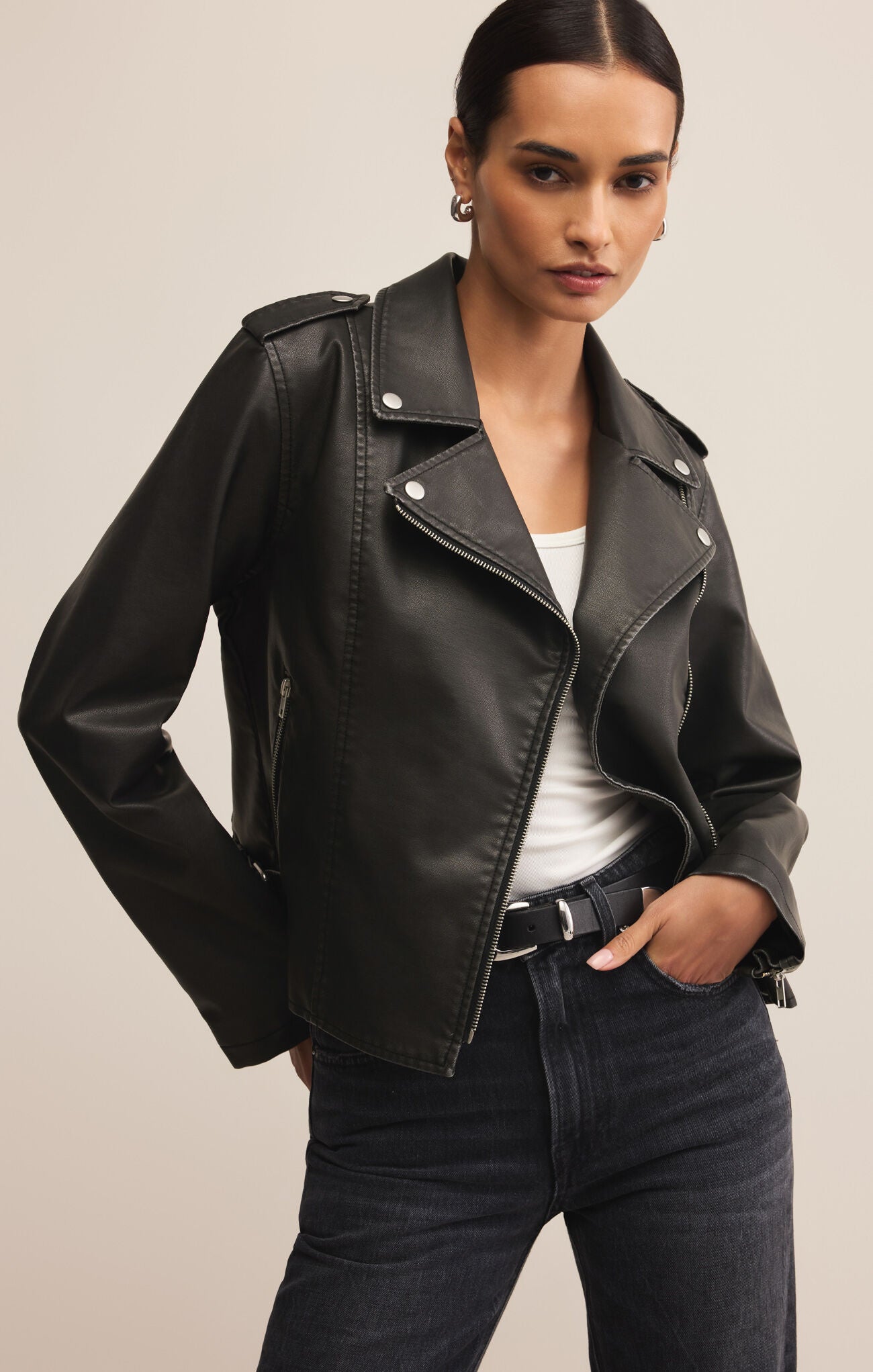 Woman wearing a black leather jacket with a plain background