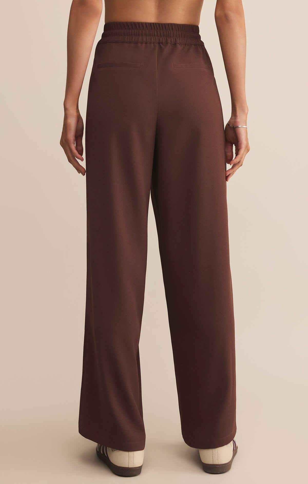 Brown pants worn by a person on a beige background