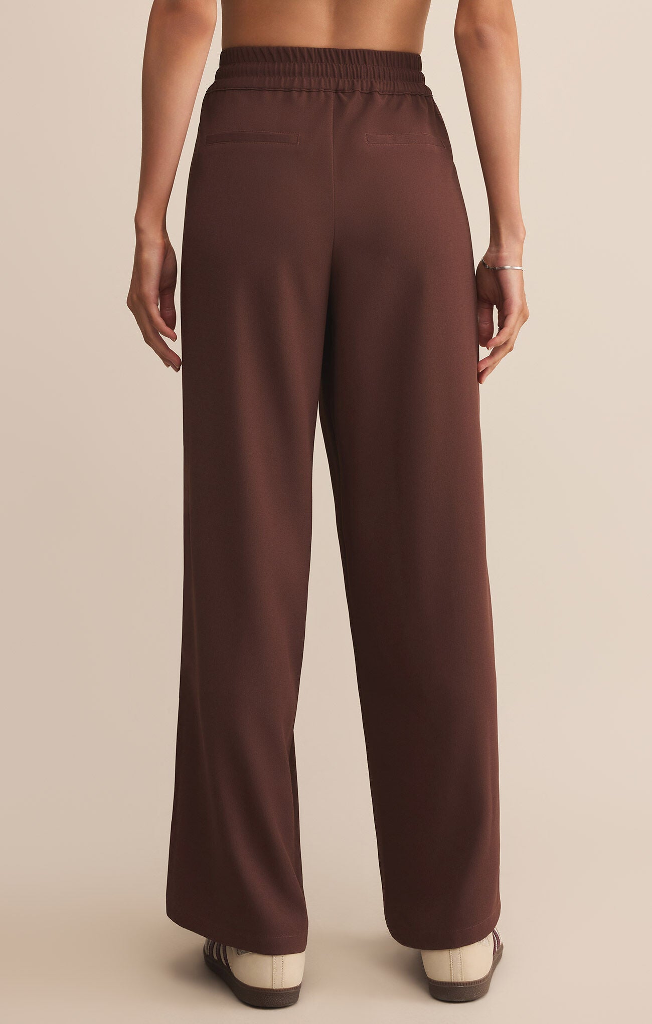 Brown pants worn by a person on a beige background