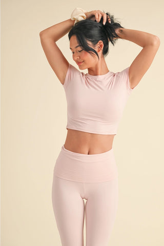 Woman wearing a pink athletic outfit against a beige background