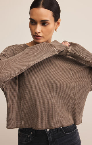 Woman wearing a brown textured top against a beige background