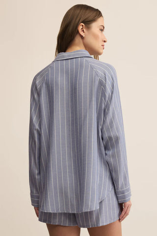 Woman wearing a blue pinstripe shirt and shorts set on a beige background