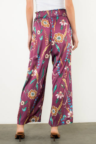 Purple floral-patterned pants worn by a person on a plain background