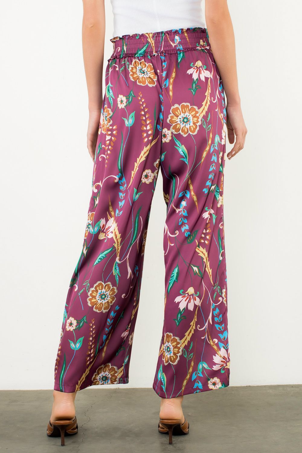 Purple floral-patterned pants worn by a person on a plain background