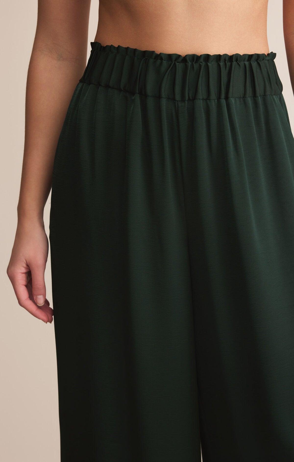 Dark green pants with an elastic waistband on a neutral background