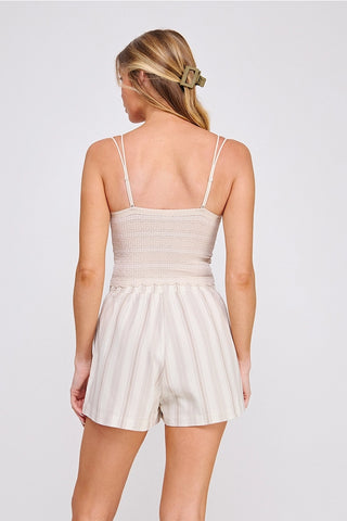 Woman wearing a beige romper against a white background