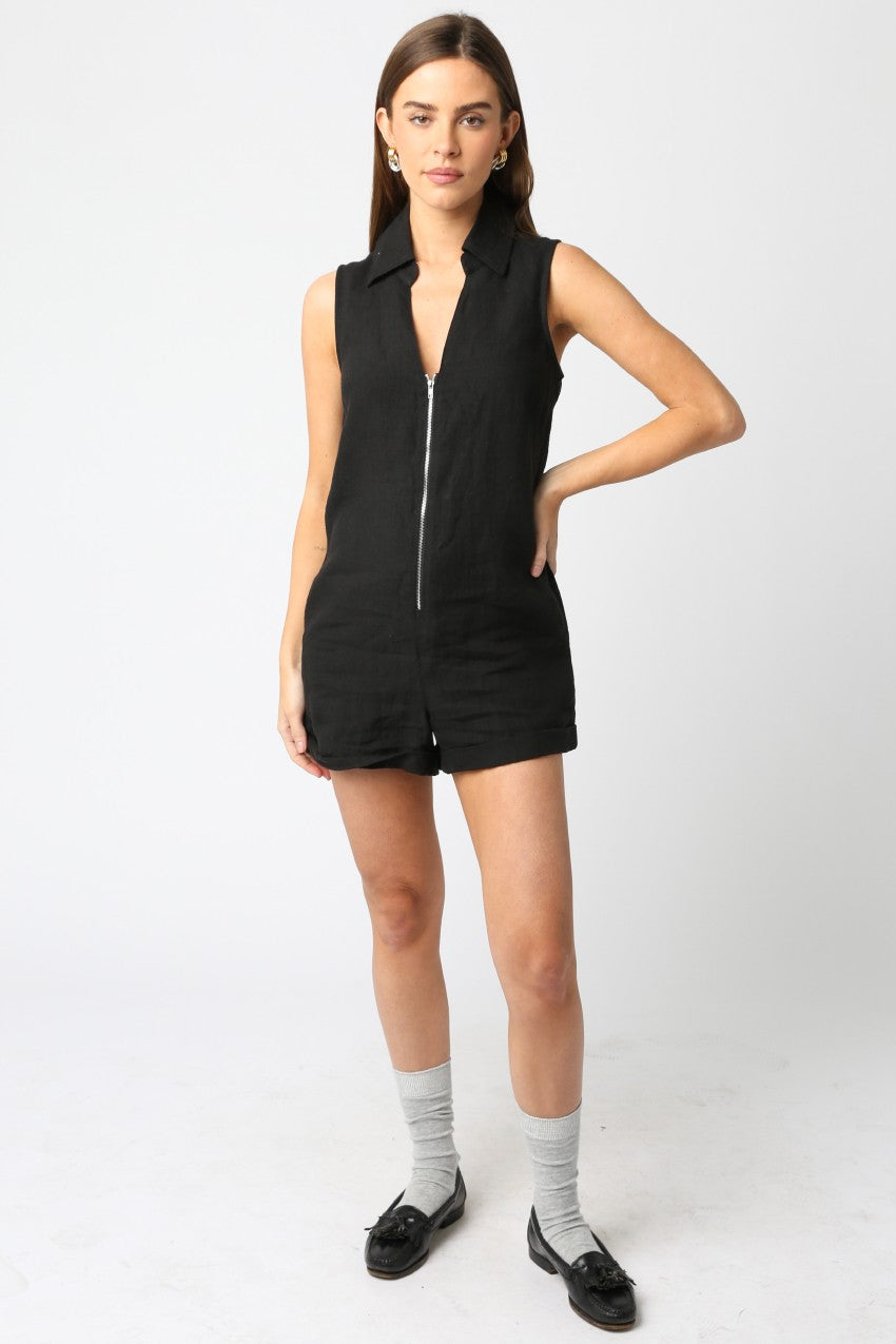Woman wearing a black sleeveless zip-up romper on a white background