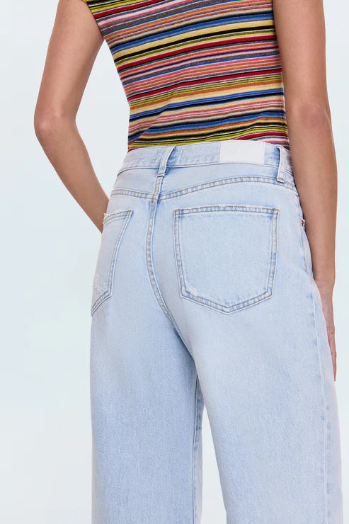 Person wearing a colorful striped top and light blue jeans on a white background